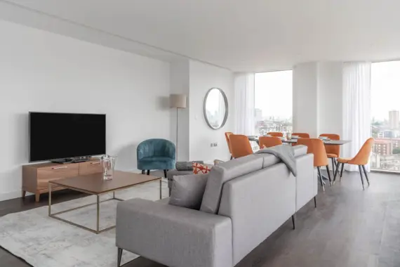 The living room boasts a light and modern aesthetic, with sleek furnishings and a minimalist design