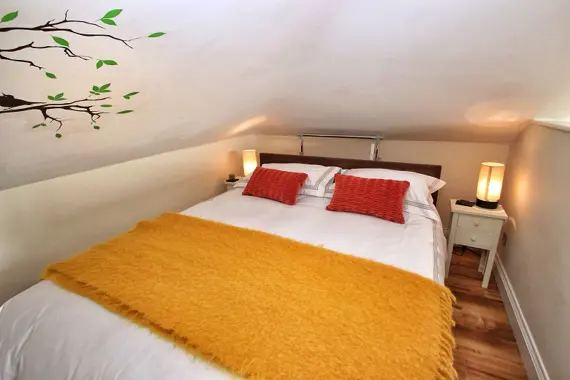 The Hill View Loft  has a king size bed with under storage, separated from the living area by a privacy wall