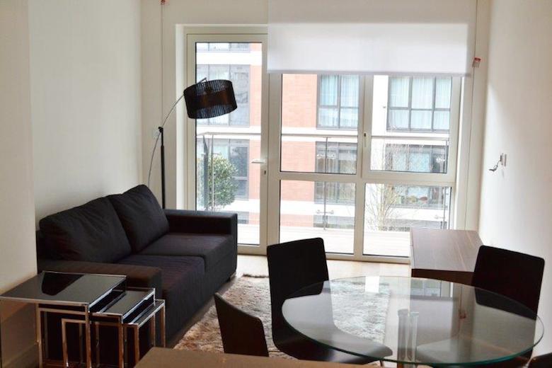 A typical open plan living area with a dining table and french doors leading to an outdoor space